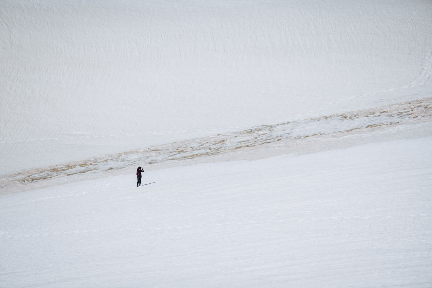 Person standing alone on vast white ice sheet