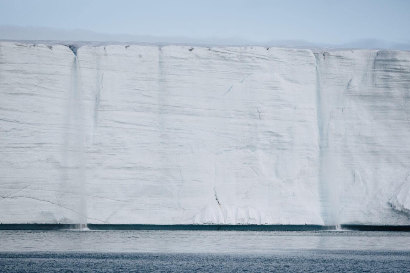 Sculptural white glacier walls meeting dark water