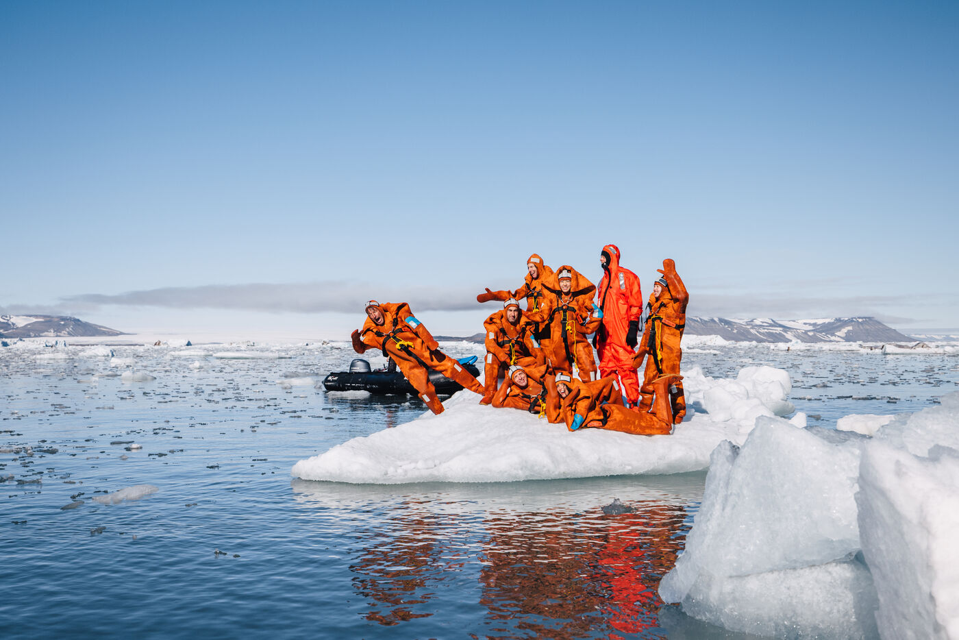 Group in bright orange lobster suits on white iceberg