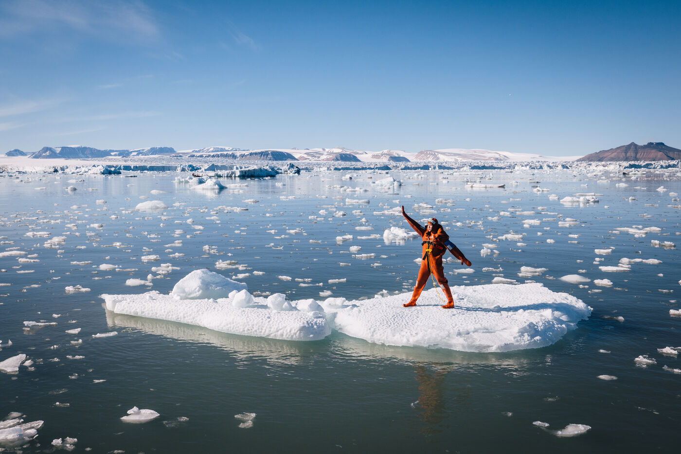 Diver in orange suit on large white iceberg
