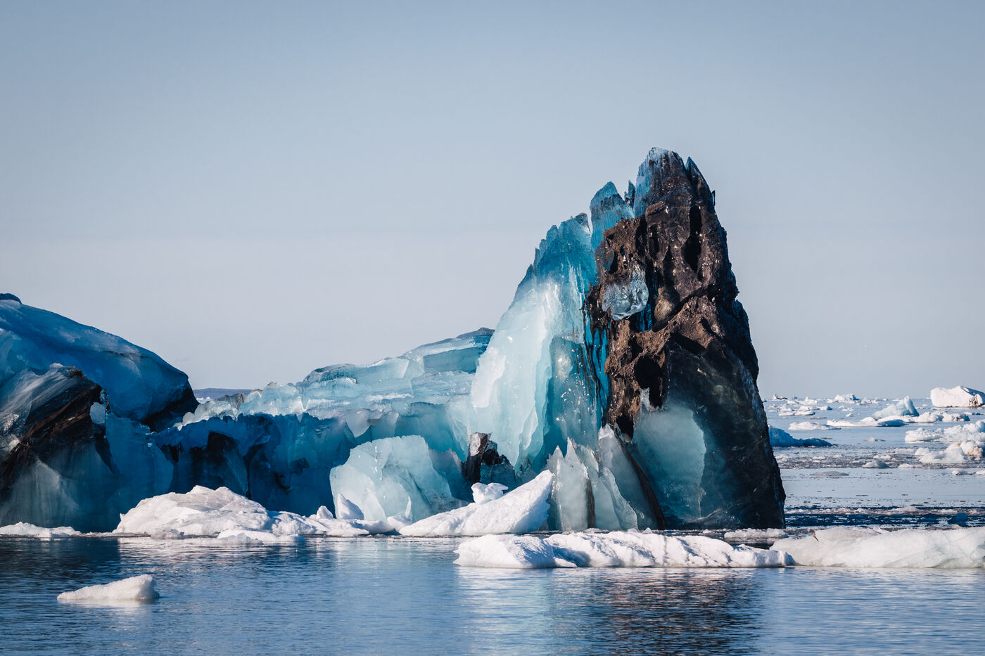Blue iceberg with a dark debris-covered crest