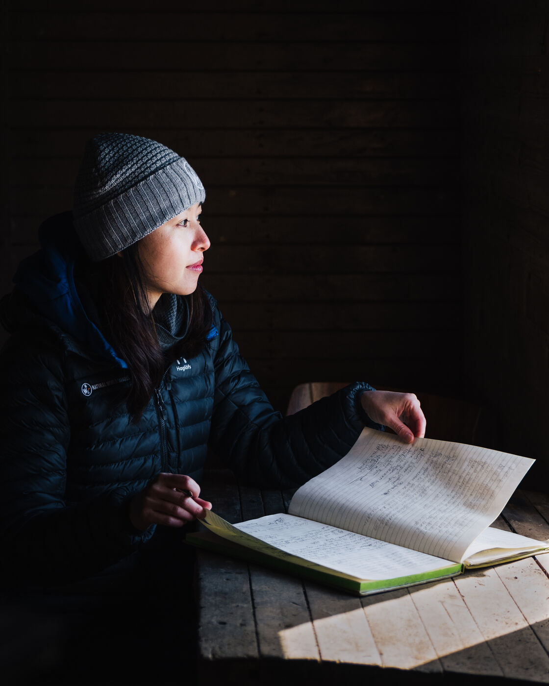 Woman in a grey beanie leafing through the cabin logbook