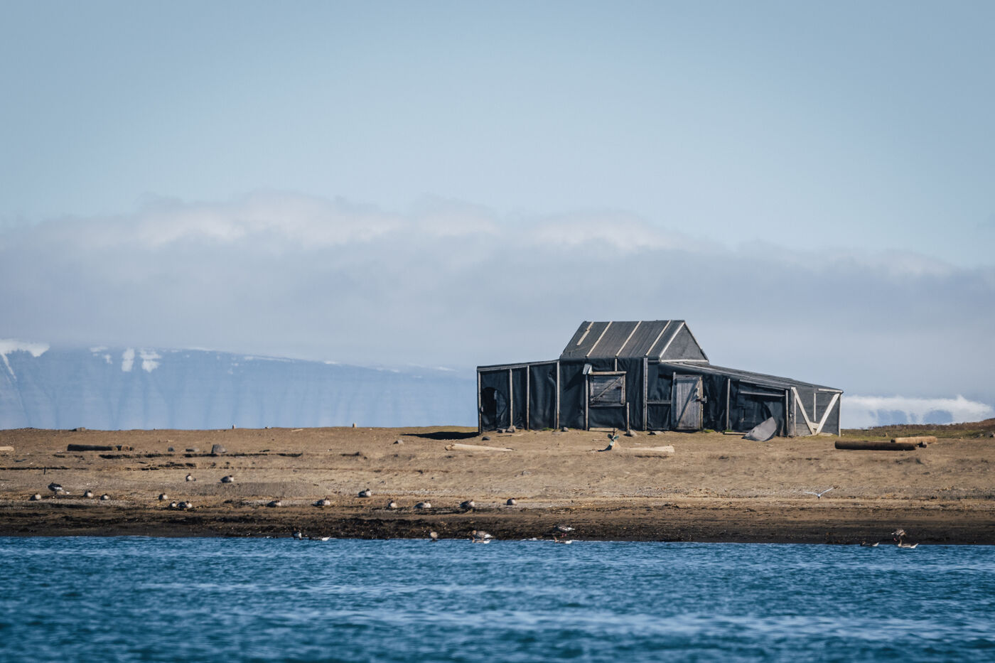 Derelict wooden structure with snow-covered mountains beyond