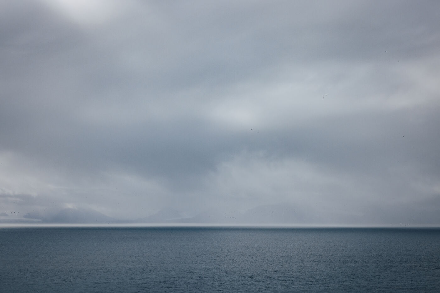 Grey sea under heavy cloud, light breaking on the horizon