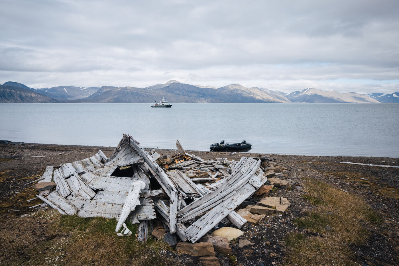 Collapsed wooden wreck on the shore, a zodiac and the Kinfish anchored beyond