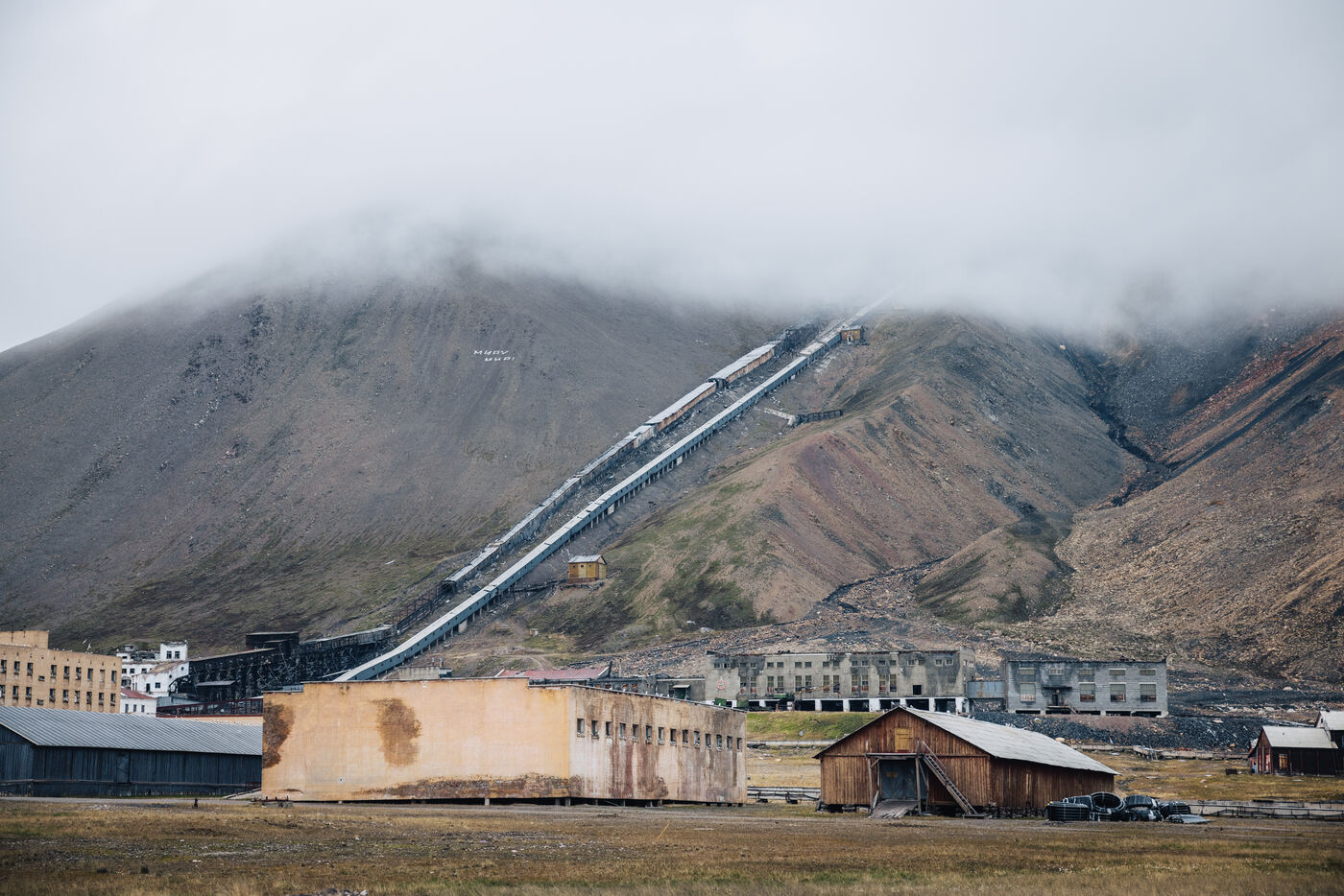 Wide view of Pyramiden with the mine conveyor climbing the mountainside under low cloud