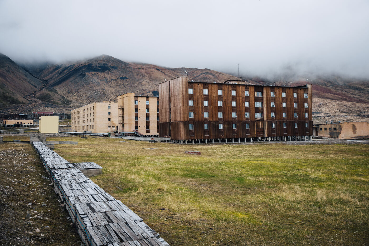 Wooden apartment block beside a raised timber boardwalk across the grass