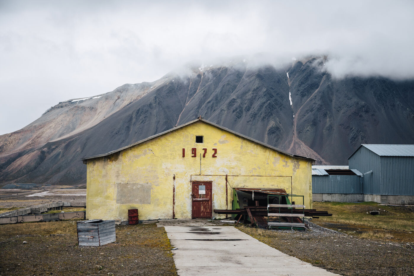 Yellow building marked 1972 with a mountain behind