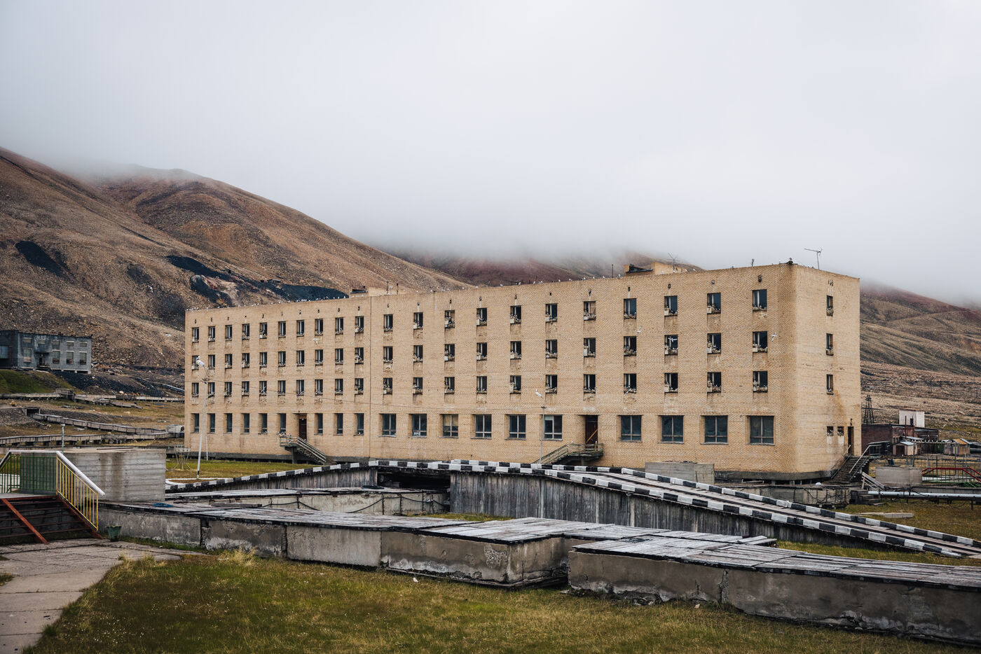 Tan apartment block below fog-covered slopes