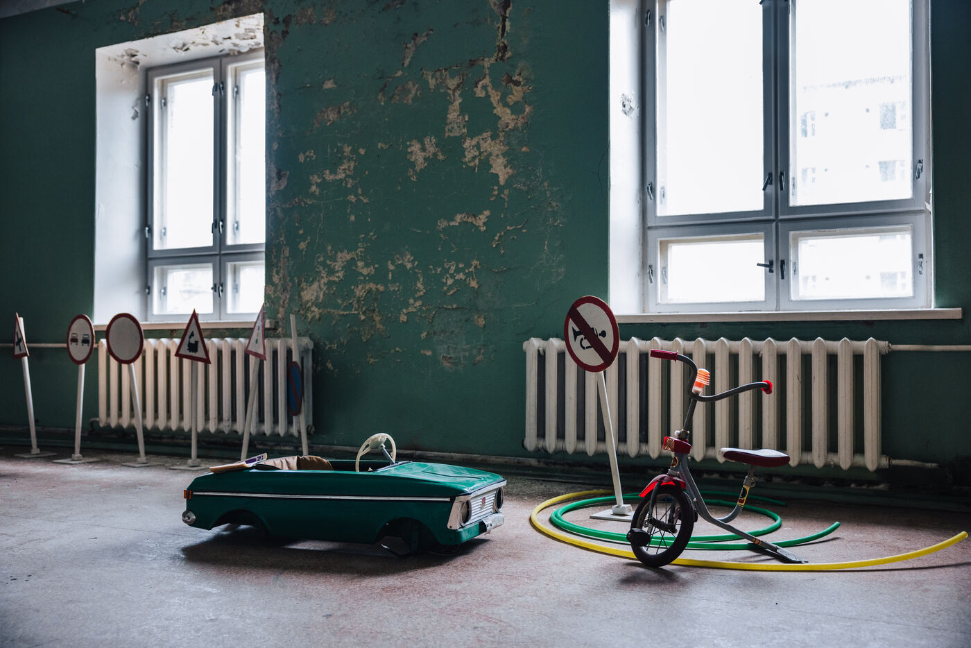 Abandoned playroom with a toy pedal car, tricycle and miniature traffic signs