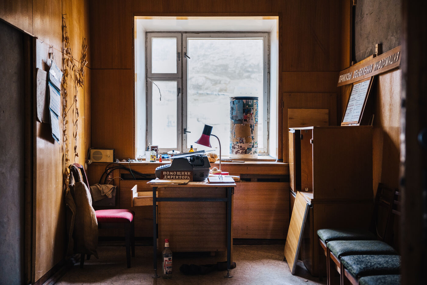 Abandoned office with a typewriter and desk lamp beneath the window