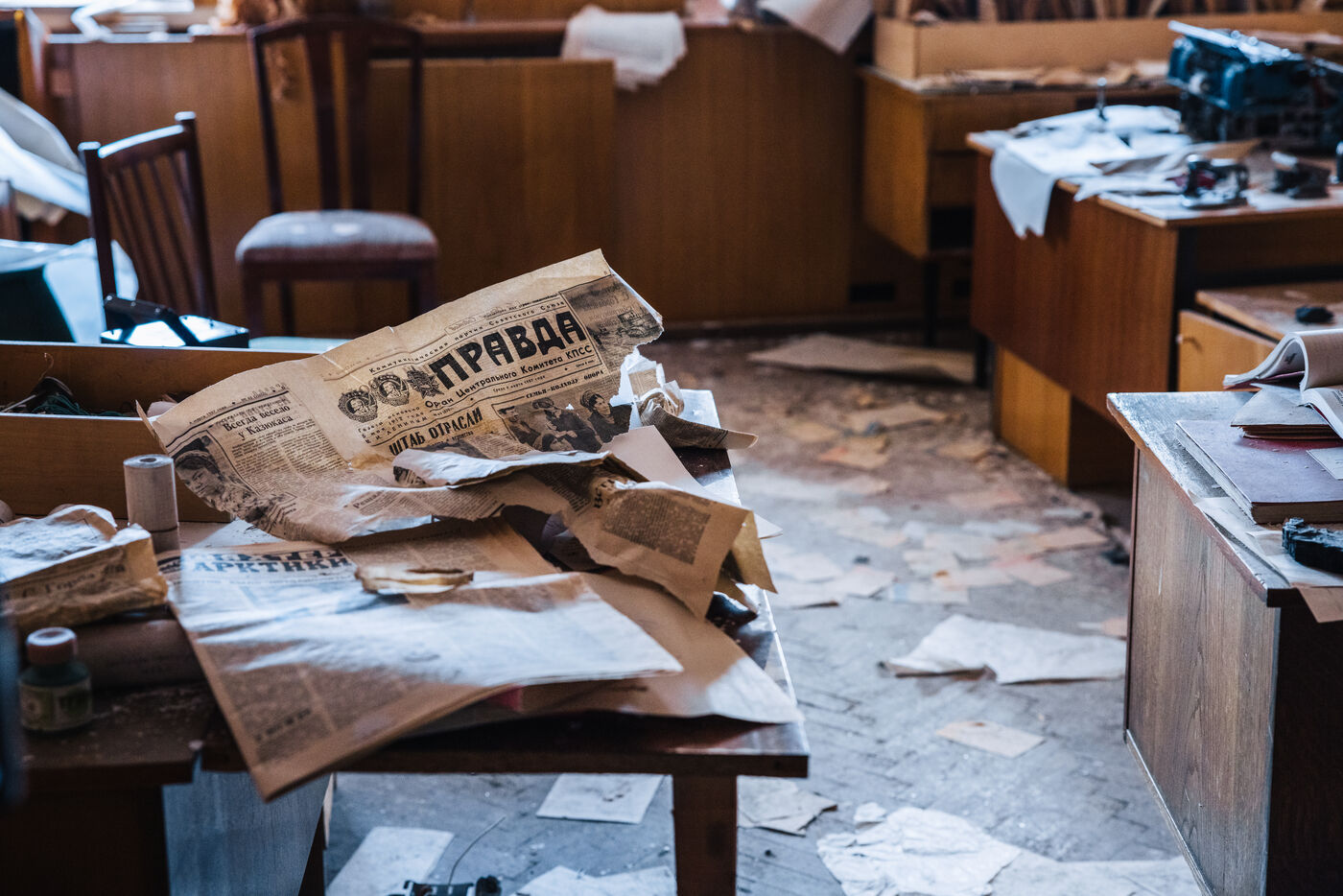 Yellowed Pravda newspapers and scattered papers on an office desk