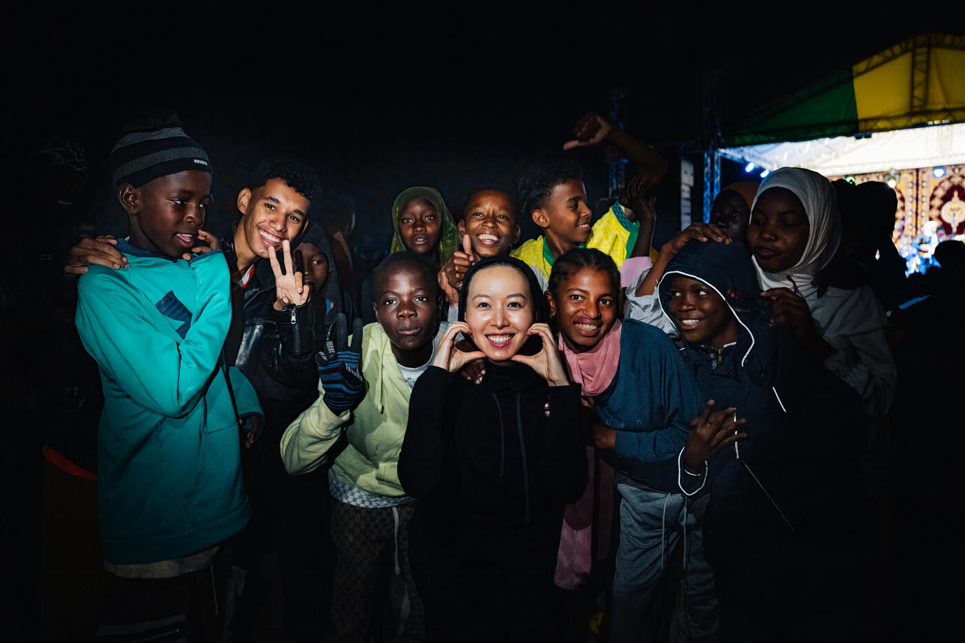 Nighttime group photo with local children at the concert grounds, one of us making a heart with her hands