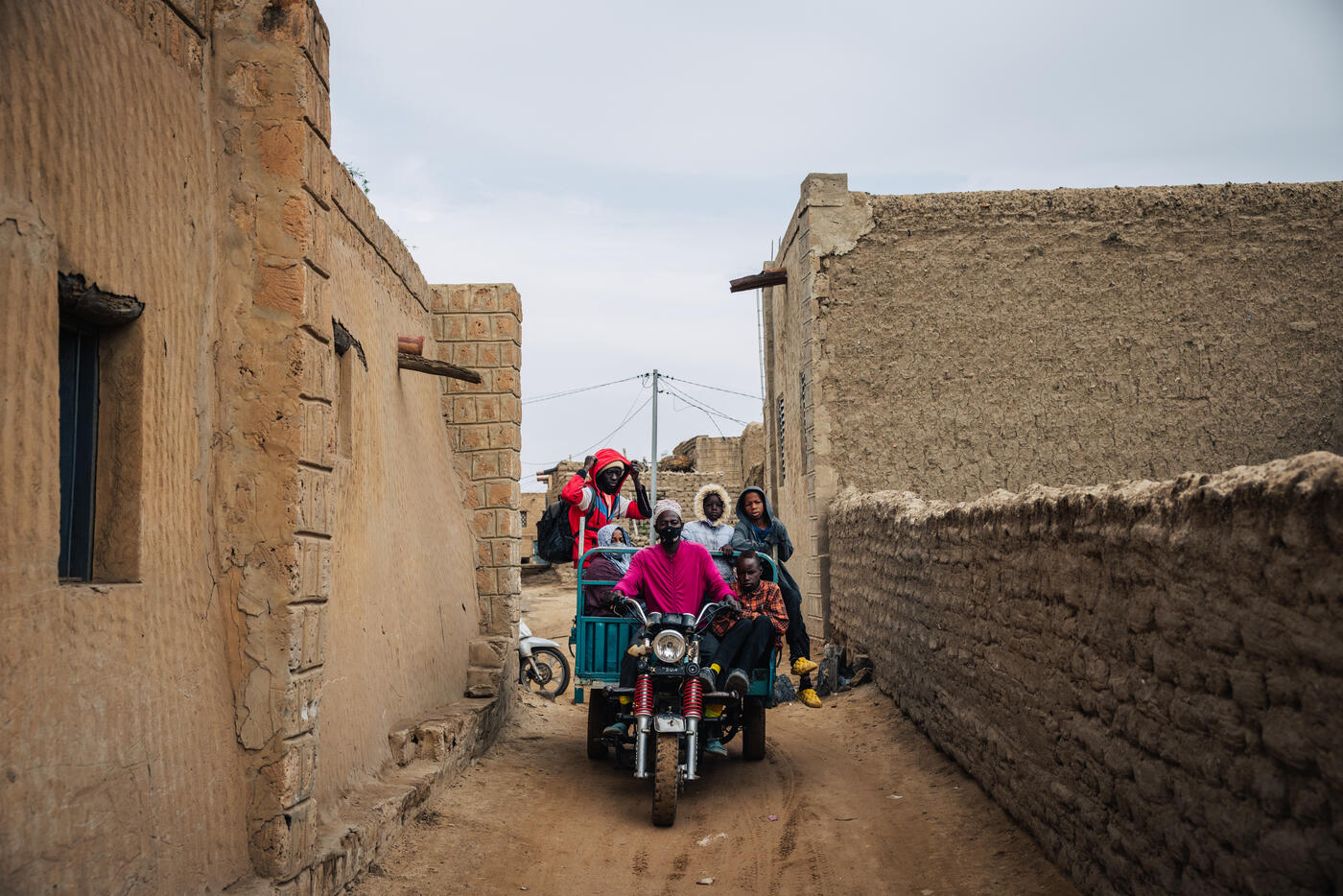 People on motorcycle in narrow mud-brick alley