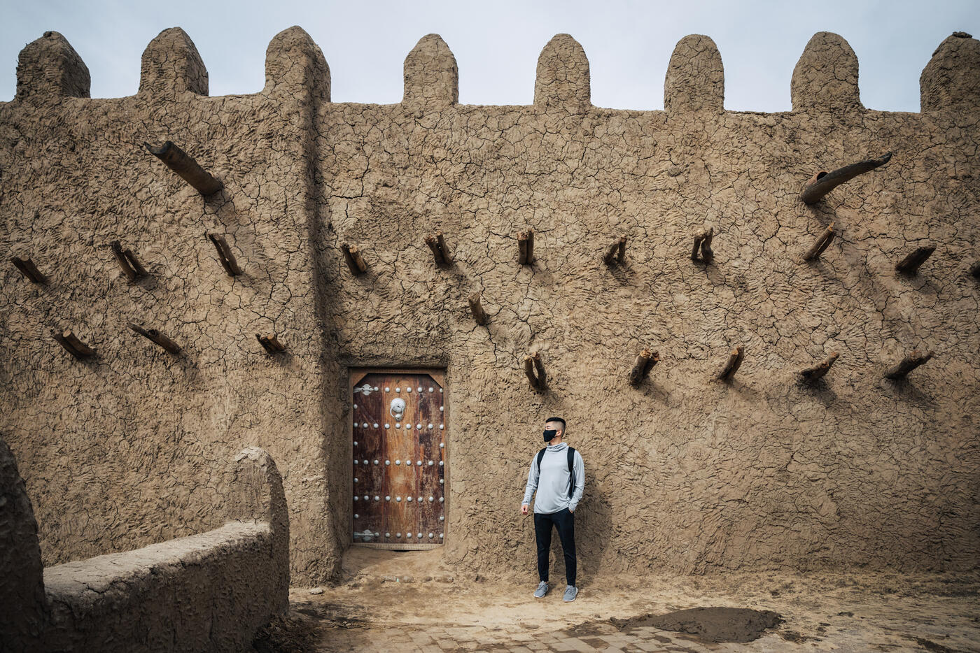 Person at mosque wall with carved door