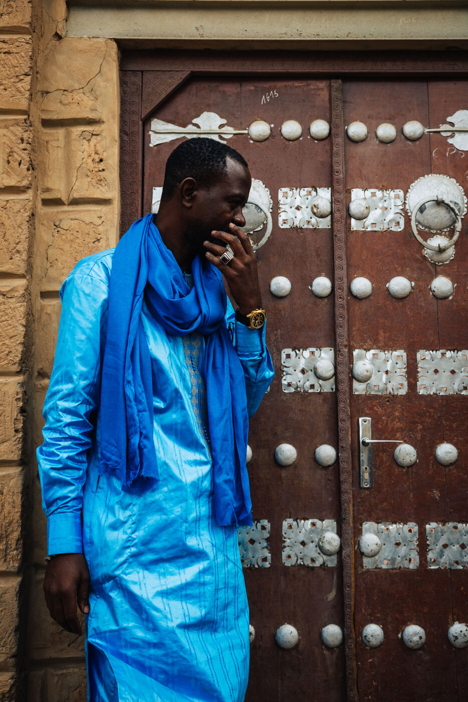Man in blue robe at ornate metal door of Sidi Yahia Mosque