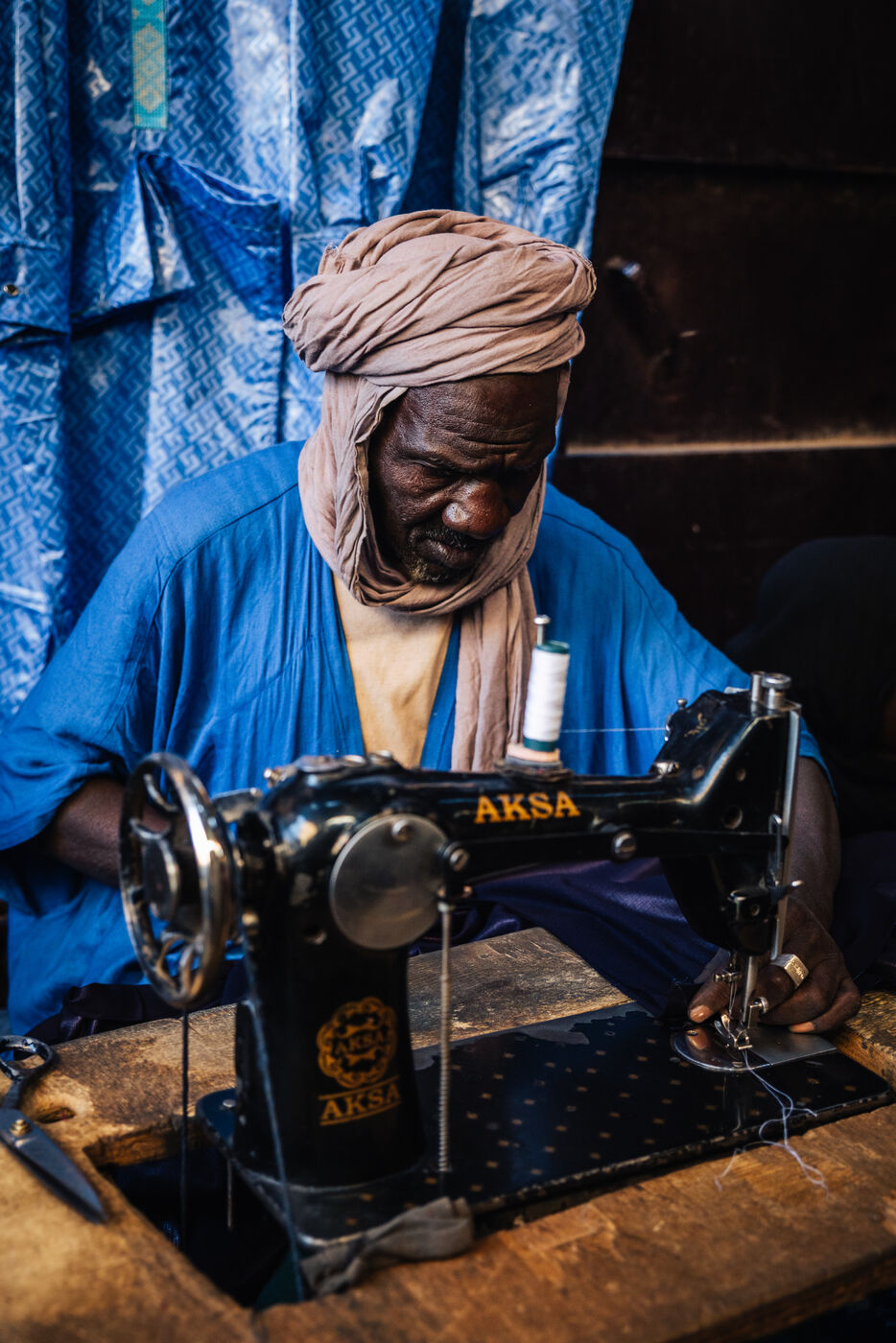 Tailor at AKSA sewing machine in market stall