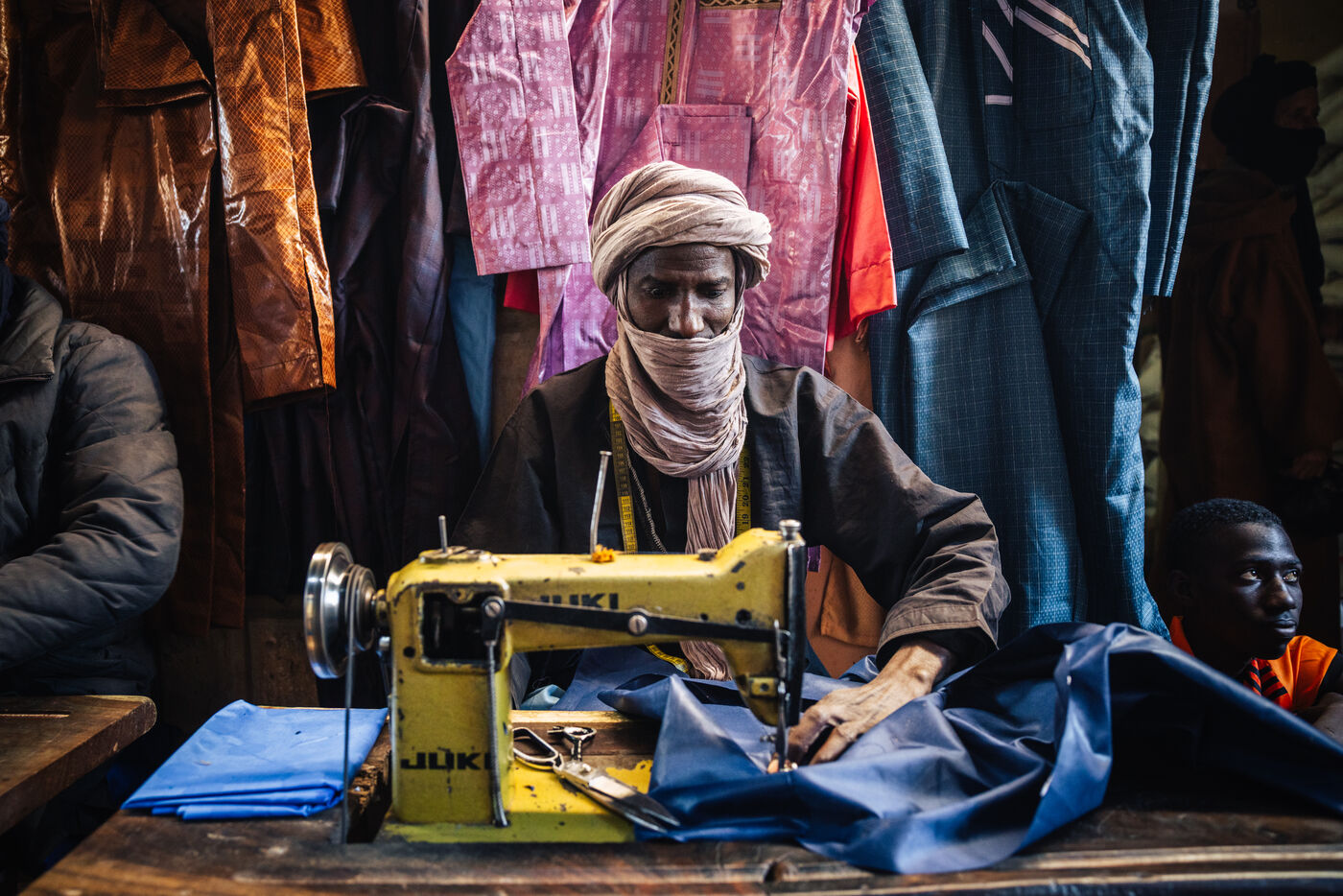 Tailor at JUKI sewing machine in market stall