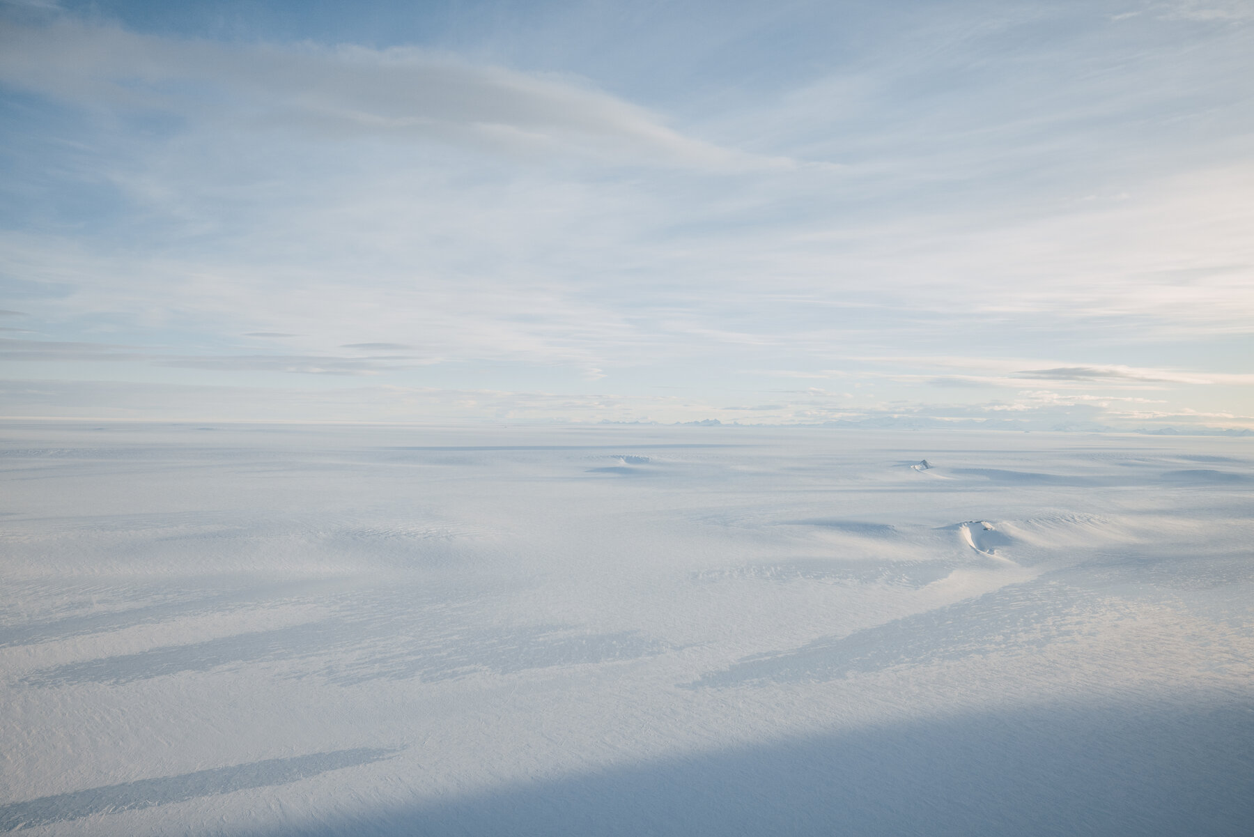 First aerial view of the Antarctic plateau through the private jet window on descent