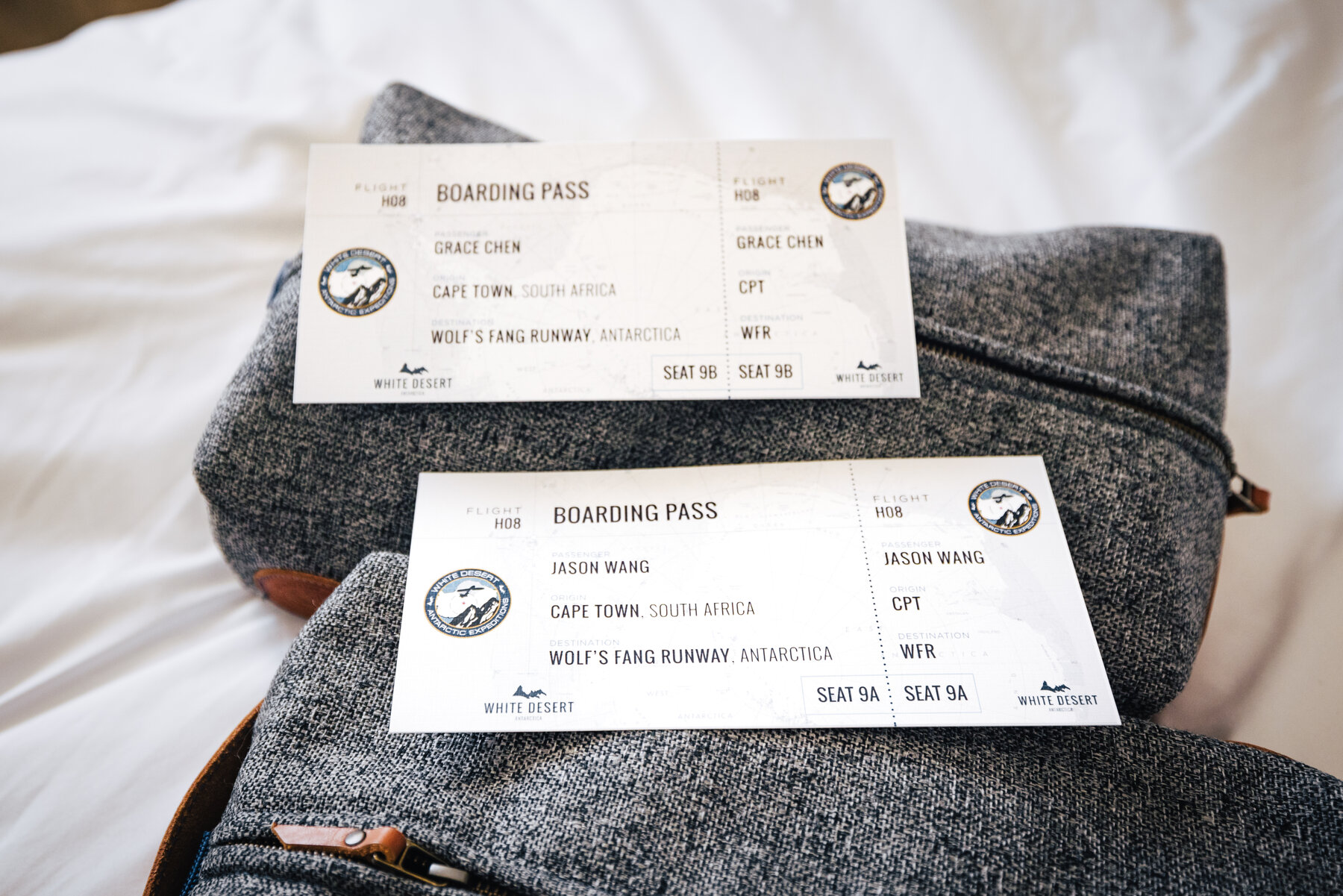 Two White Desert boarding passes for Jason Wang and Grace Chen showing Cape Town to Wolf's Fang Runway, Antarctica on gray duffel bags