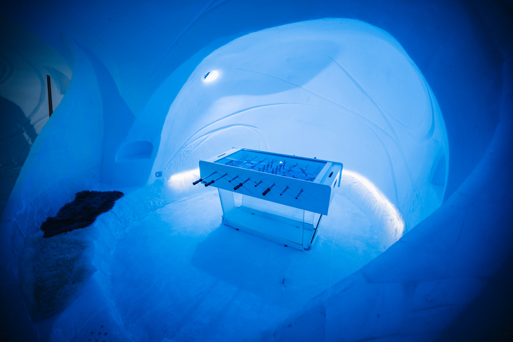 Foosball table inside the blue glacial ice lounge at Wolf's Fang with curved luminous ice walls