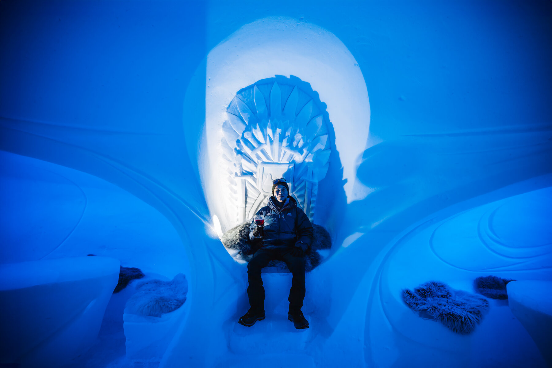 Jason seated on a sculpted ice throne inside the blue glacial ice lounge at Wolf's Fang