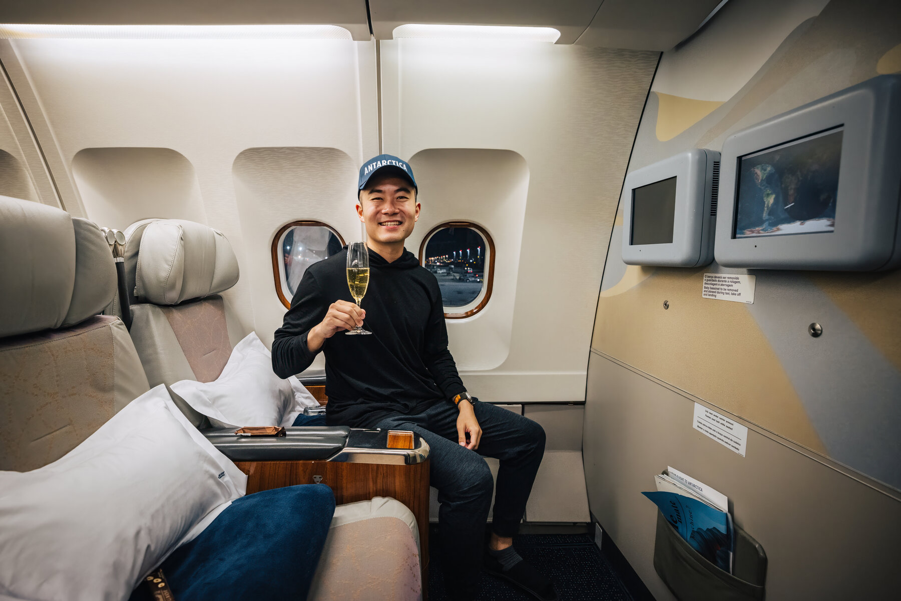 Jason holding a champagne flute in the private jet cabin en route to Antarctica