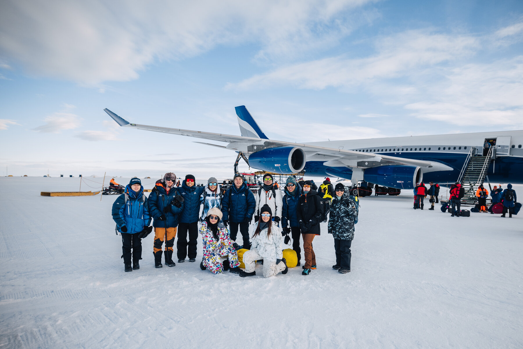 The full travel group assembled on the blue ice runway in front of the parked White Desert private jet