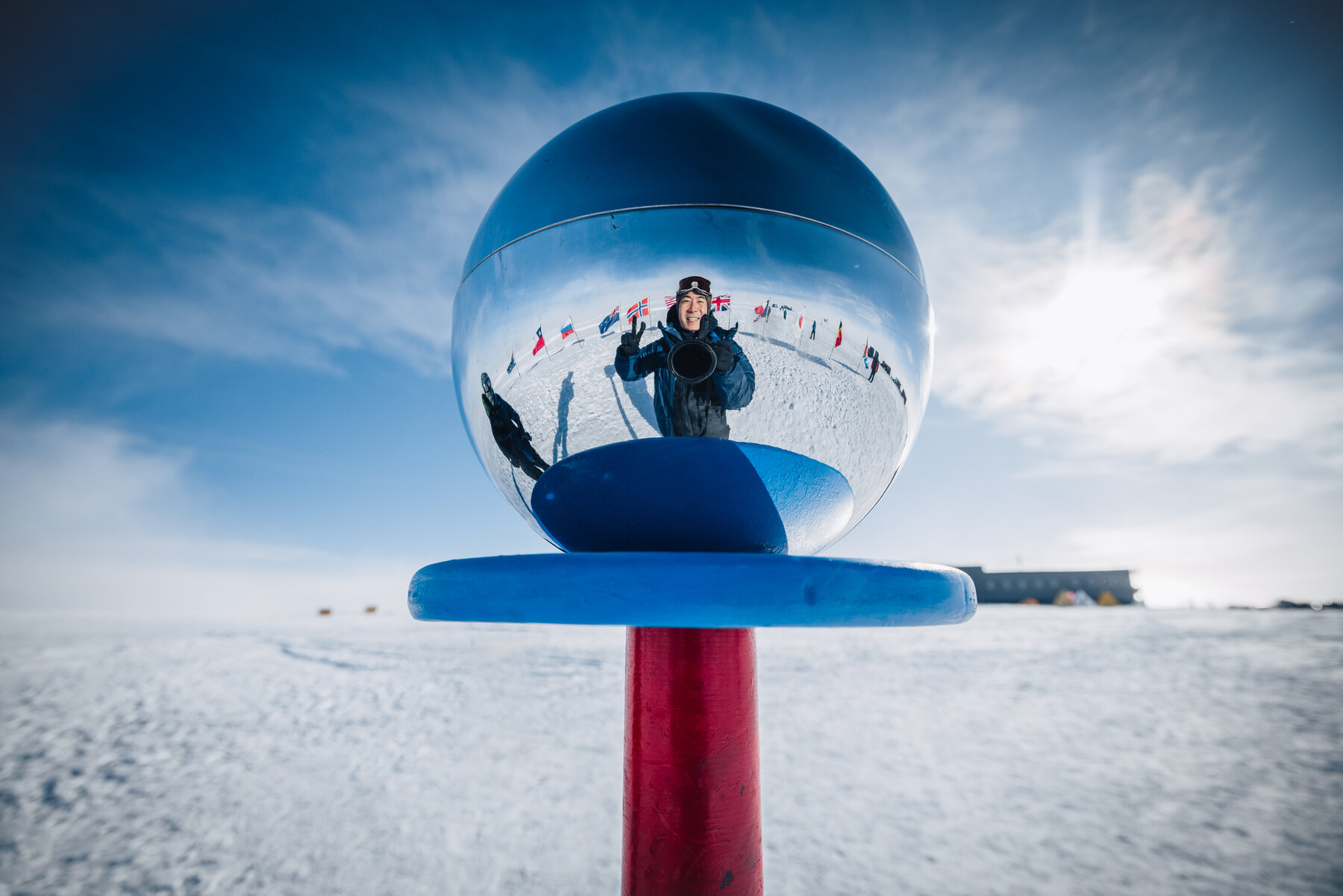 Jason reflected in the mirrored silver sphere atop the ceremonial South Pole marker