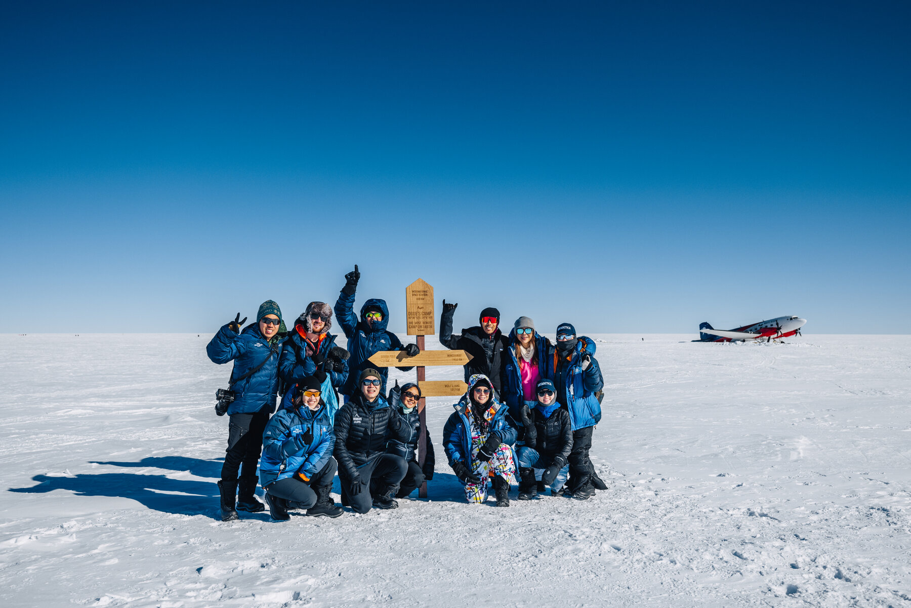 Group of travelers gathered around the Dixie's Camp directional signpost on the polar plateau