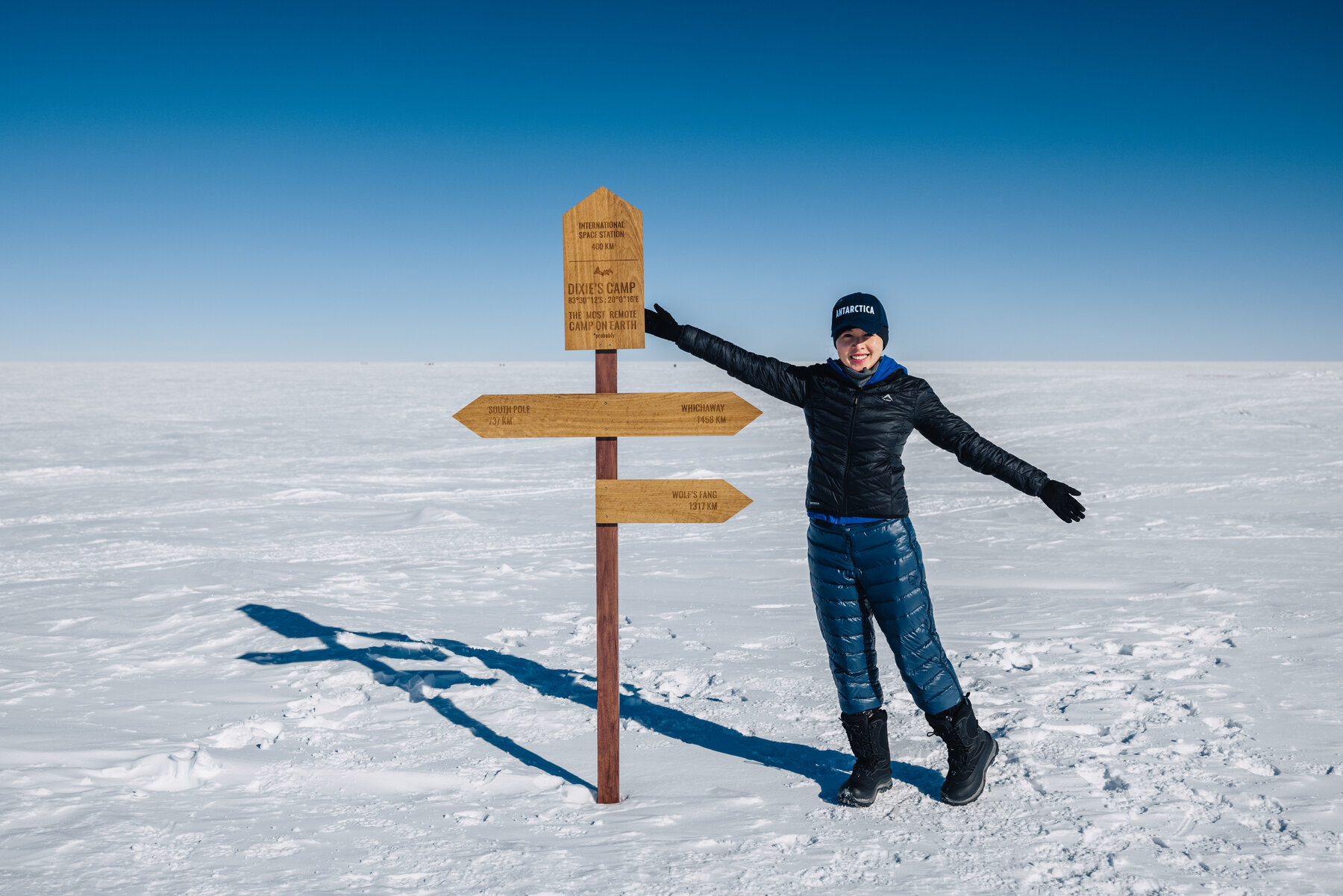 Grace posing at the wooden Dixie's Camp directional signpost on the polar plateau