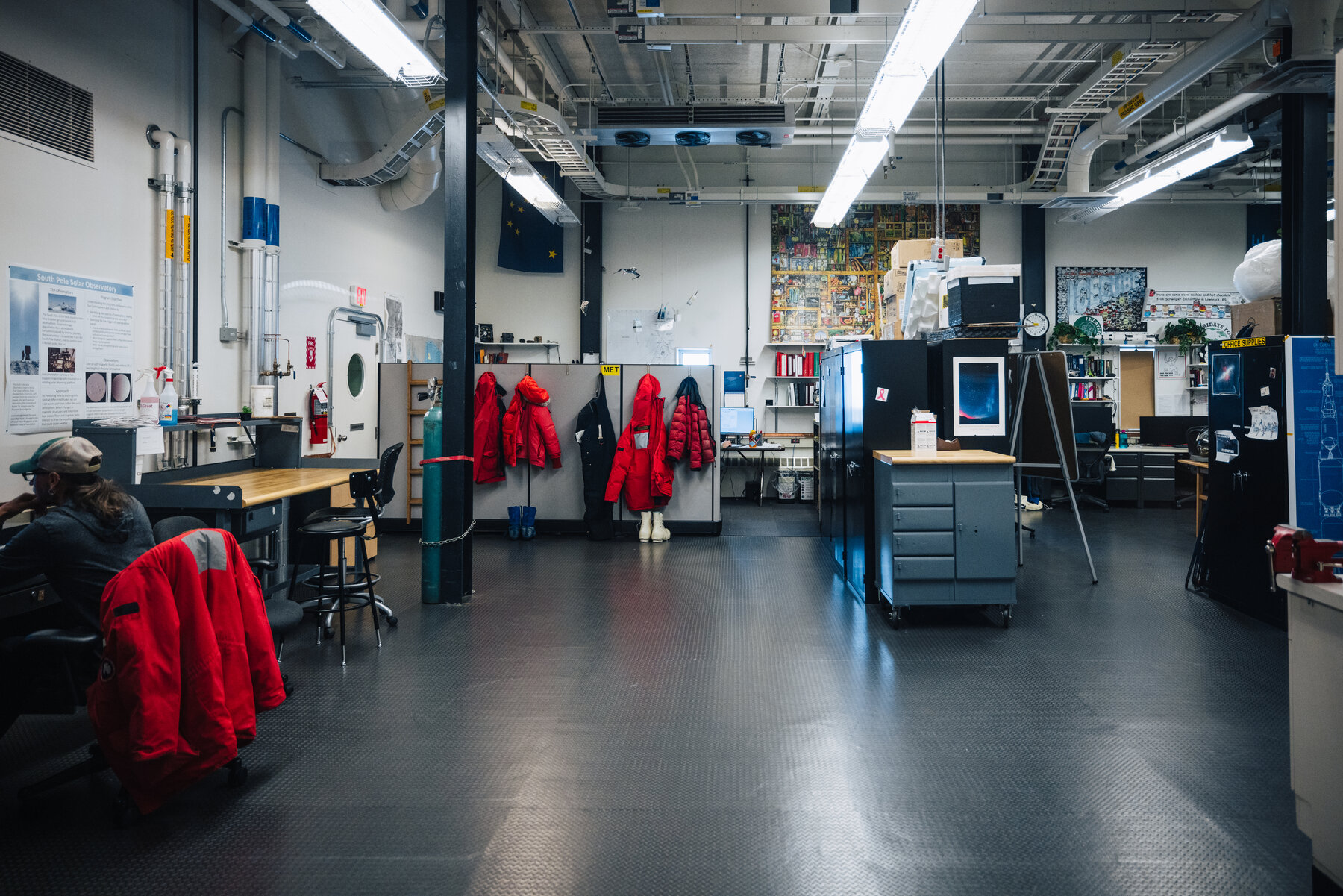 A handful of red extreme-cold-weather parkas hanging in a workshop room inside the Amundsen-Scott South Pole Station