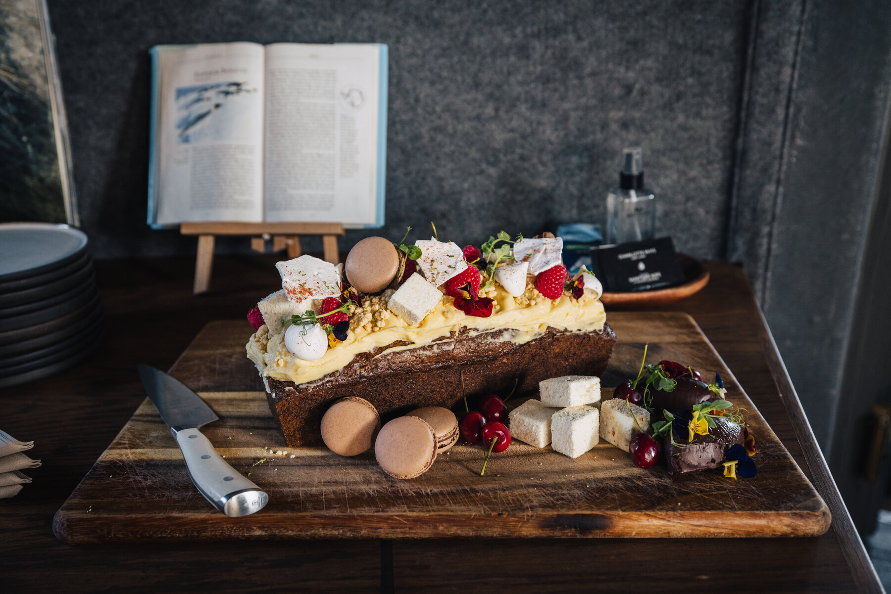 Dessert and cheese board at Whichaway with cake, macarons, triple-cream brie, strawberries, and cherries arranged on a rustic wooden board