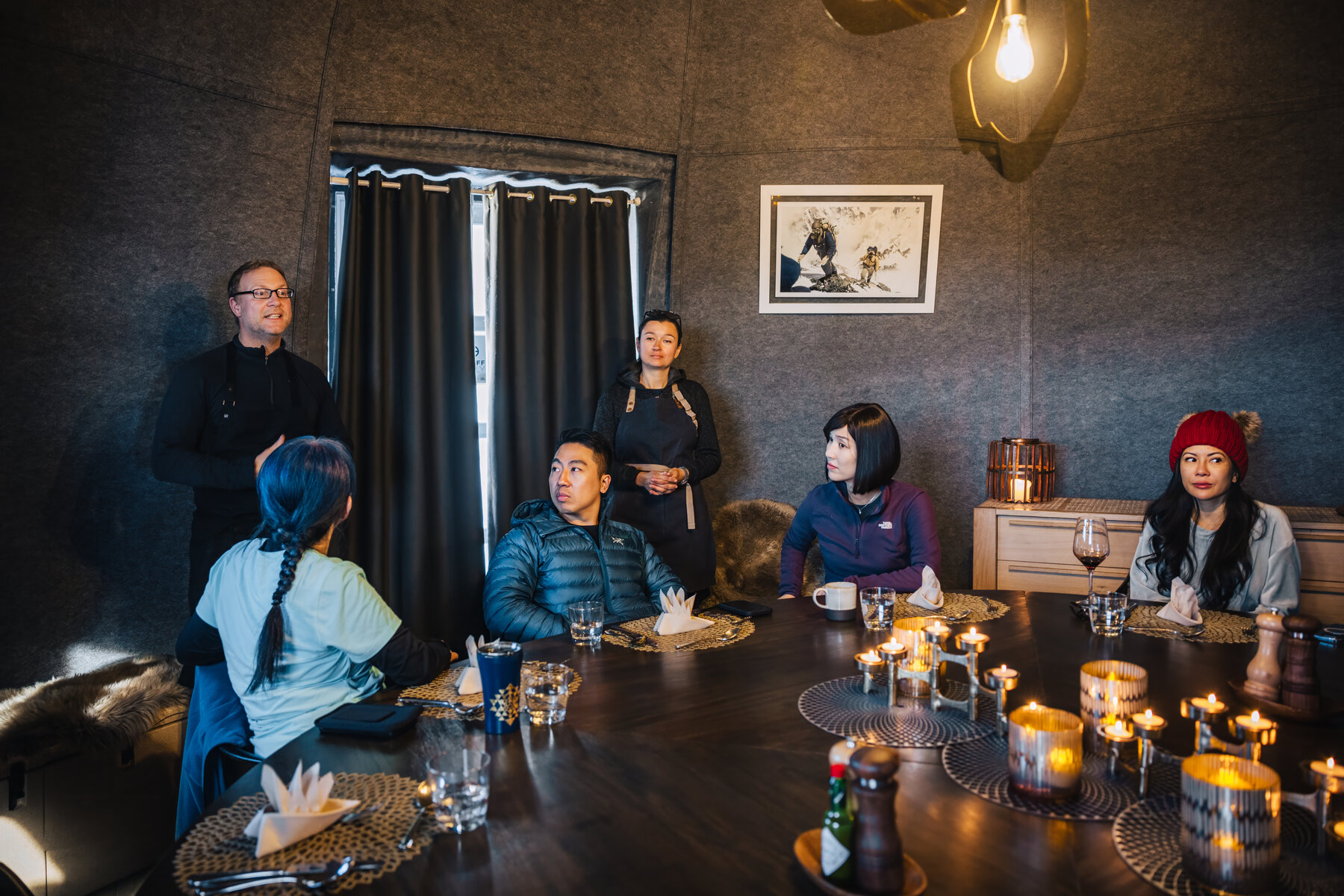 Our group gathered around the candlelit dining table at Whichaway listening to the chef introduce a course, with a painting behind and warm lighting throughout