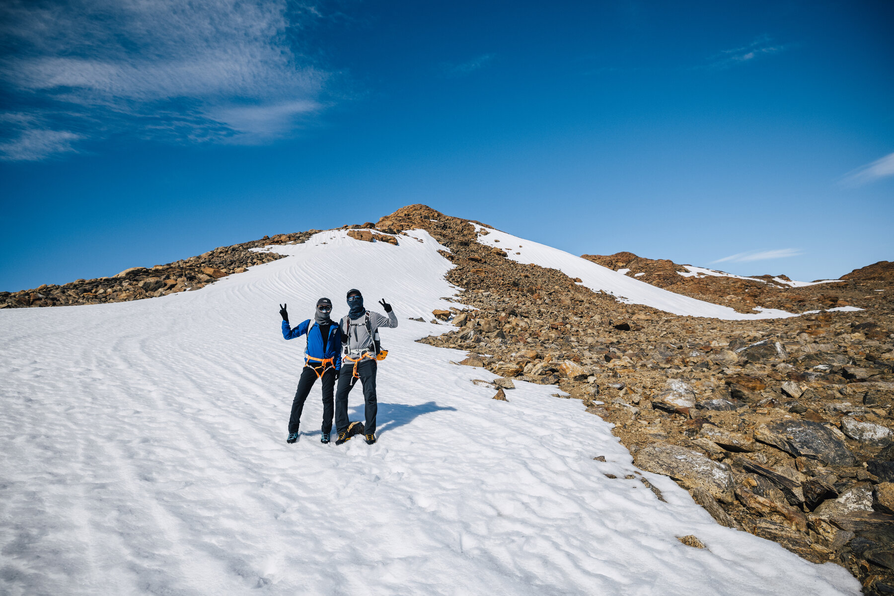 Jason and Grace in parkas making peace signs together on the Antarctic ice plateau