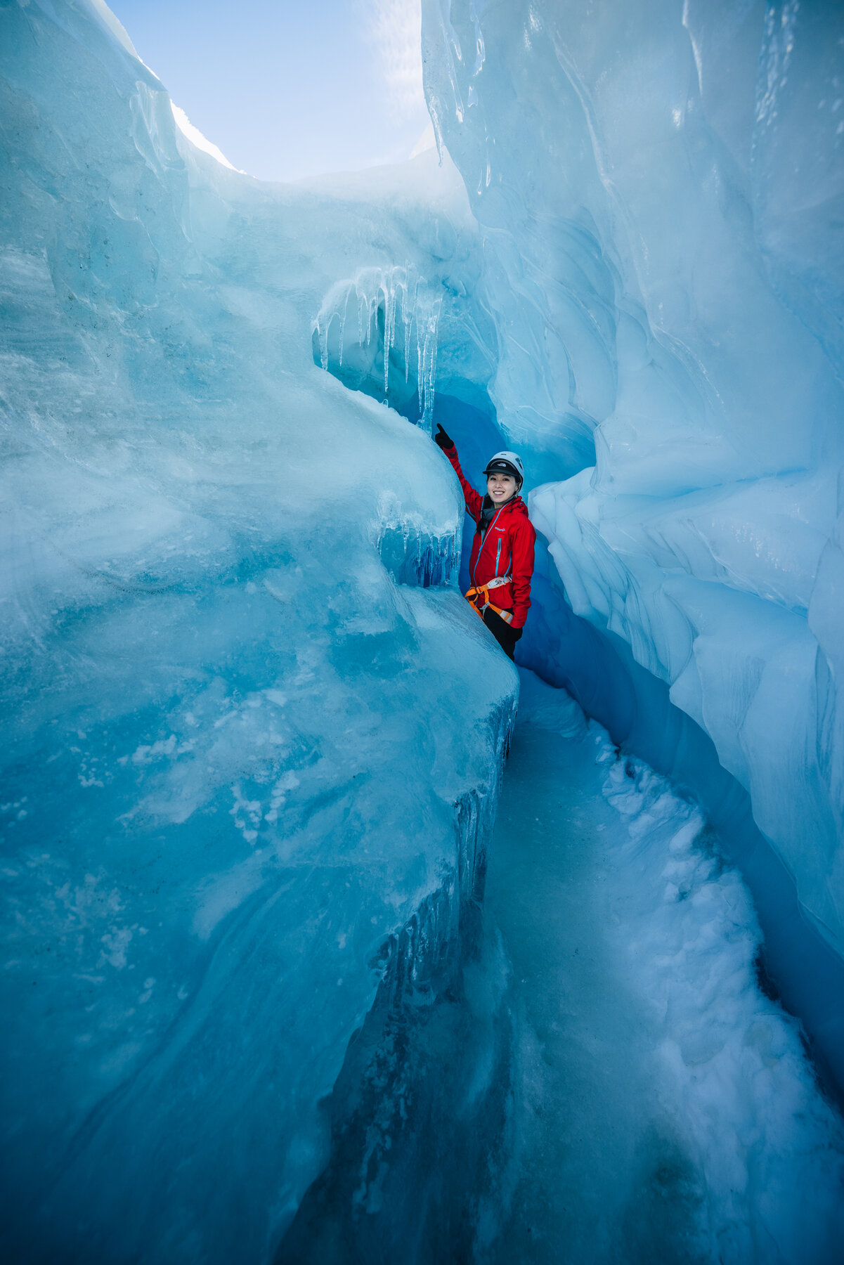 Jason squeezing through a narrow passage of a deep blue glacial crevasse