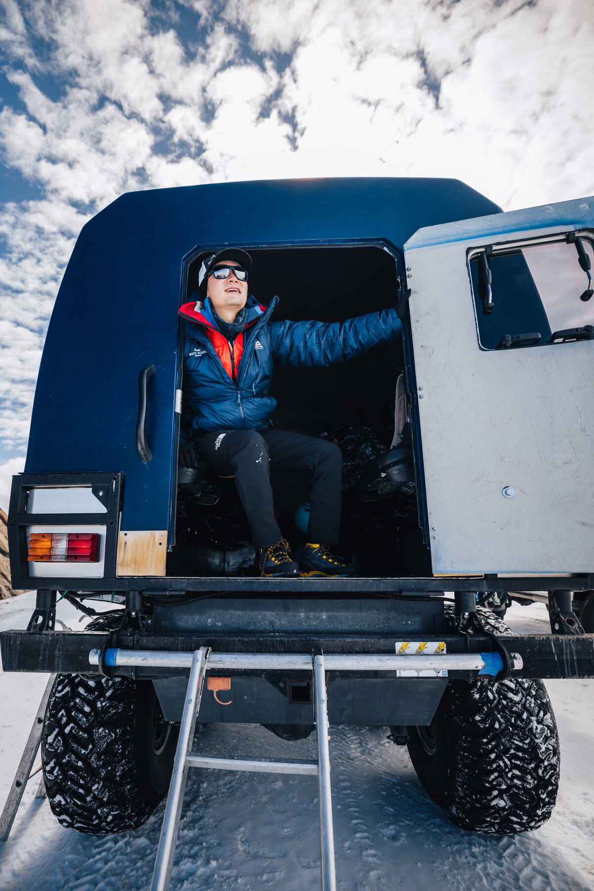 Jason sitting in the rear cabin of White Desert's custom six-wheel Antarctic expedition truck with the door open