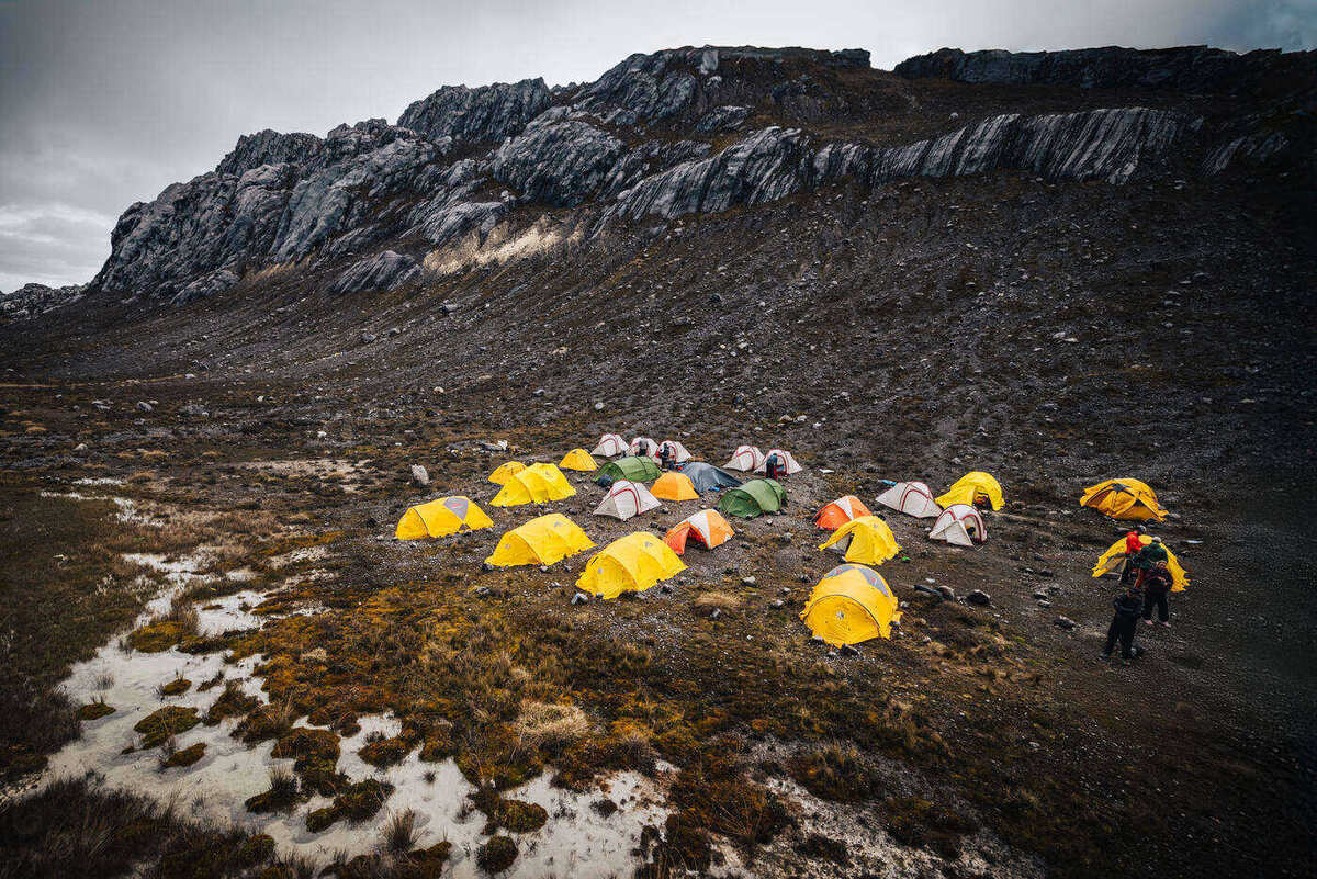 Tents with team members walking among them at camp