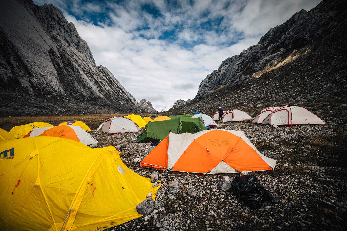 Colorful yellow, orange and green tents spread across grey rocky ground with limestone walls rising on both sides
