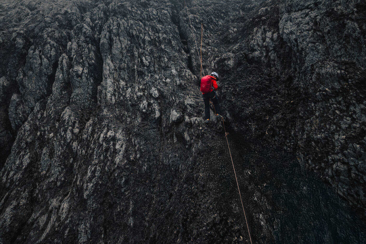 Climber rappelling down dark columnar limestone