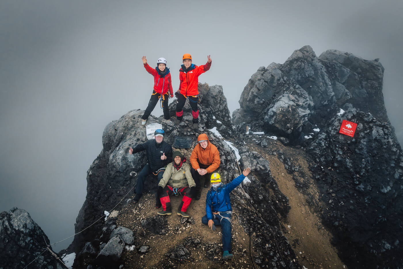Drone view of climbers on summit rocks celebrating with raised arms