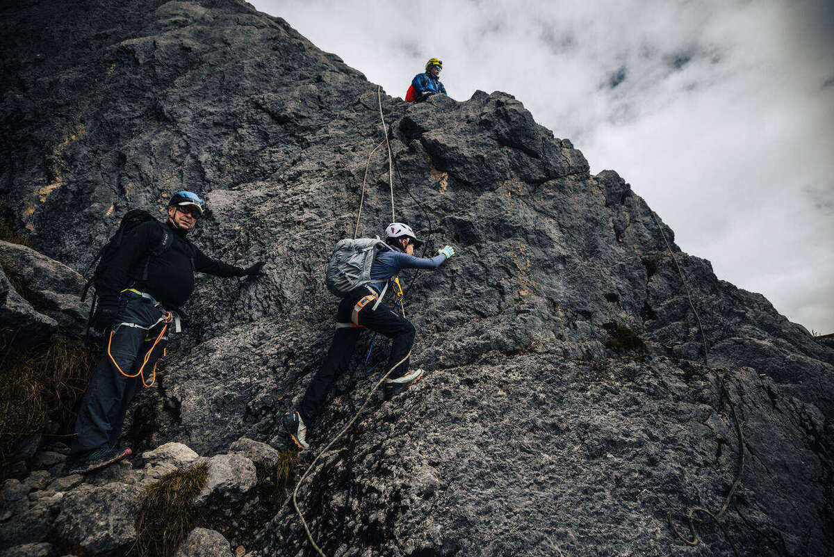 Multiple climbers on vertical limestone rock face using ropes