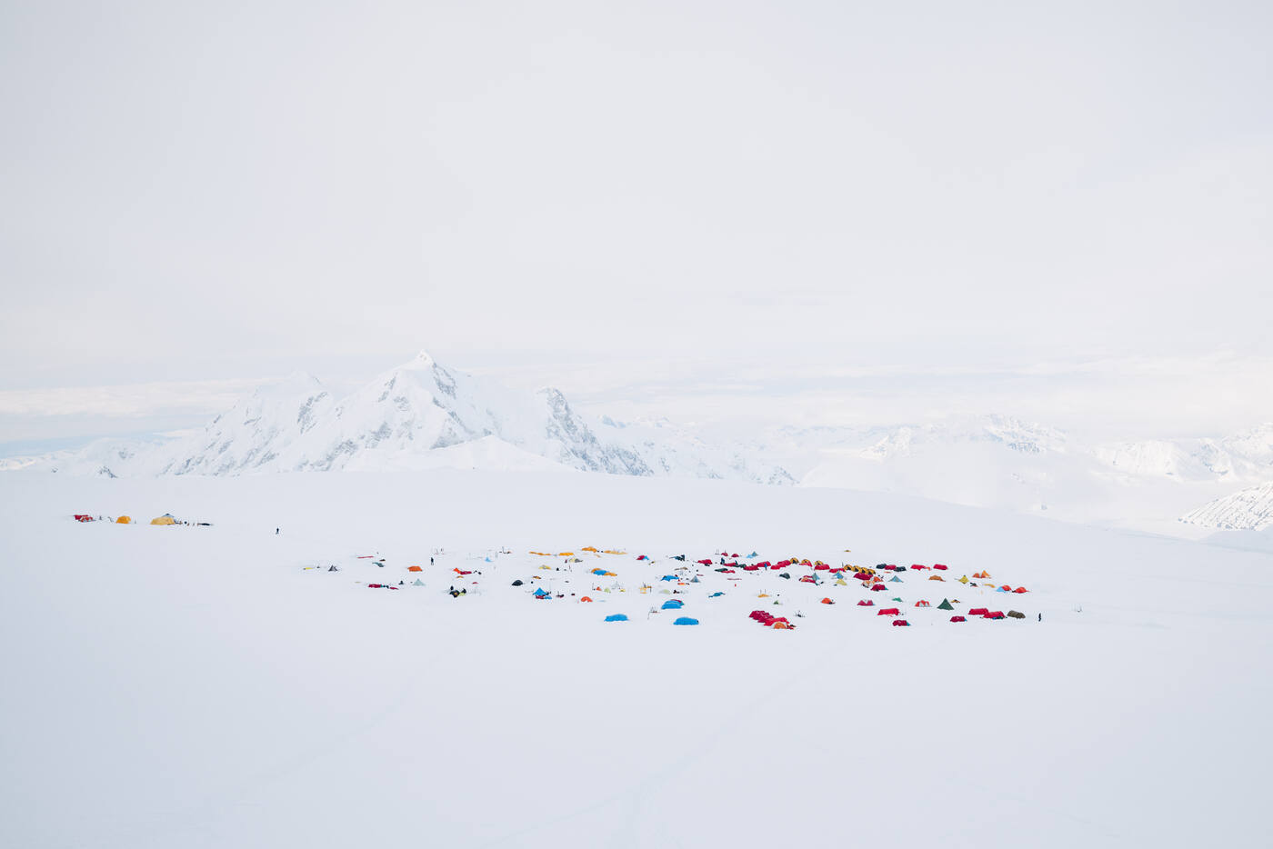 Overhead view of 14,200 ft camp on Denali with dozens of tents and climbers spread across the glacier