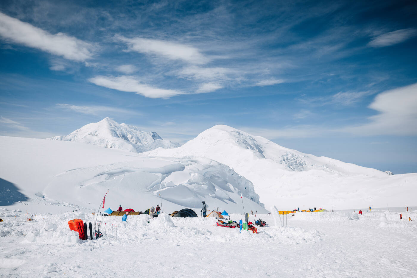 Camp setup at 11,200 feet with tents, sleds, and gear spread on the snow