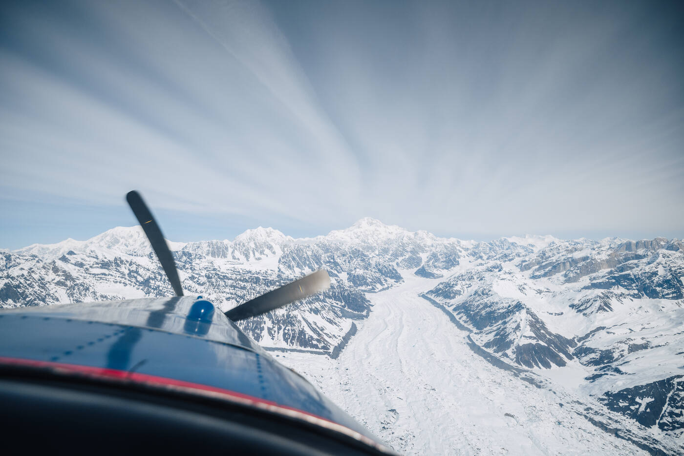 View from a bush plane flying over the Alaska Range with propeller visible and glaciers below