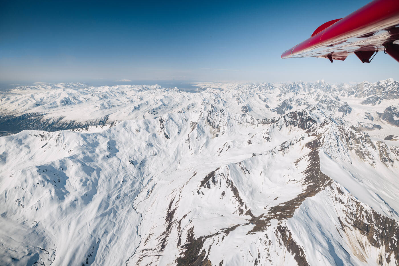 Bush plane wing with Alaska Range mountains stretching below