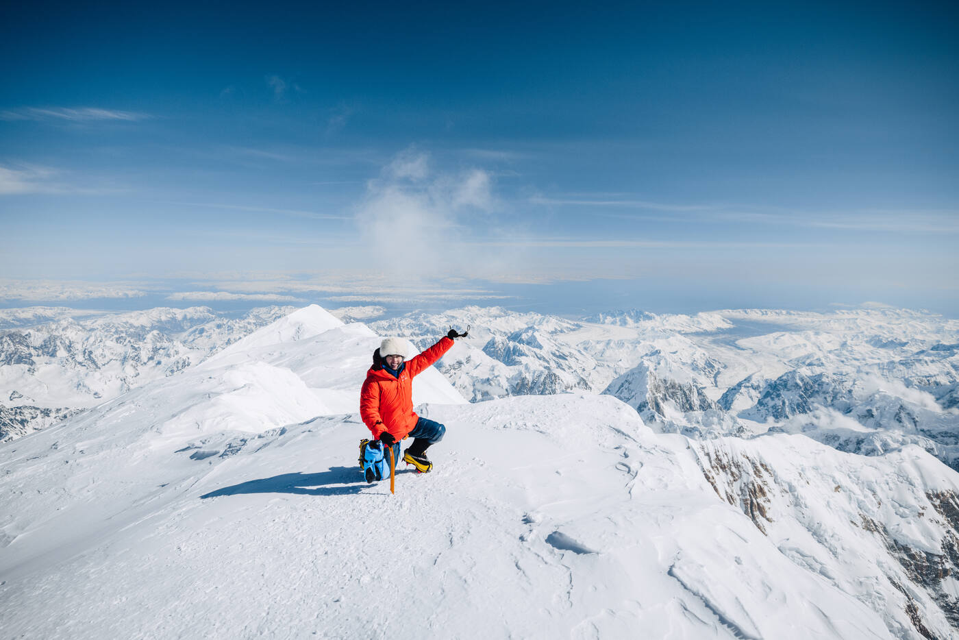 Grace kneeling at Denali summit with arm raised in celebration