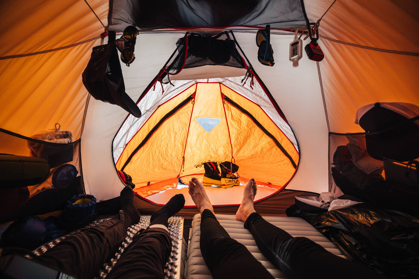 View from inside an orange tent showing sleeping pads and gear
