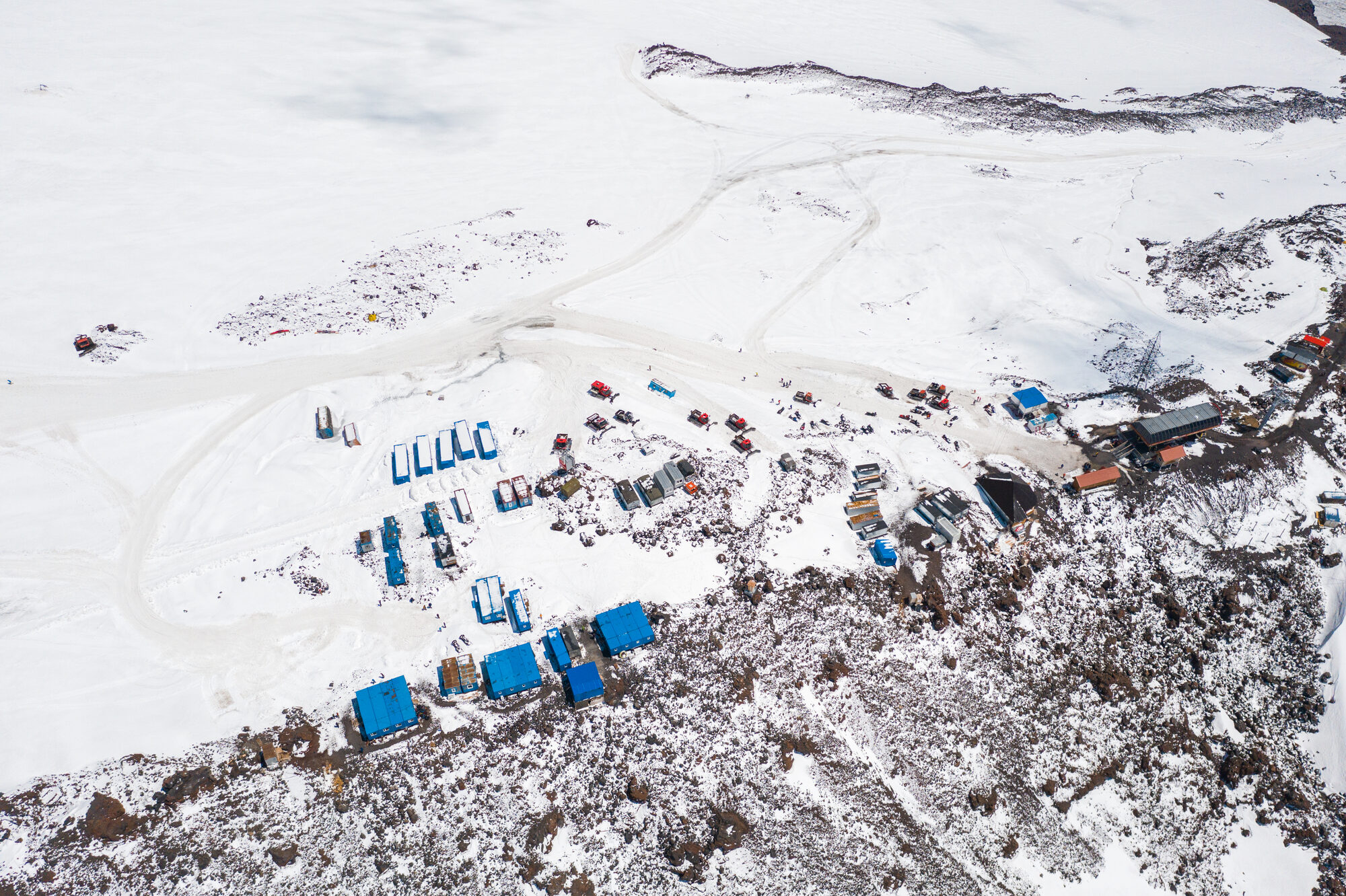Aerial drone view of Elbrus base camp showing shipping container huts in the snow