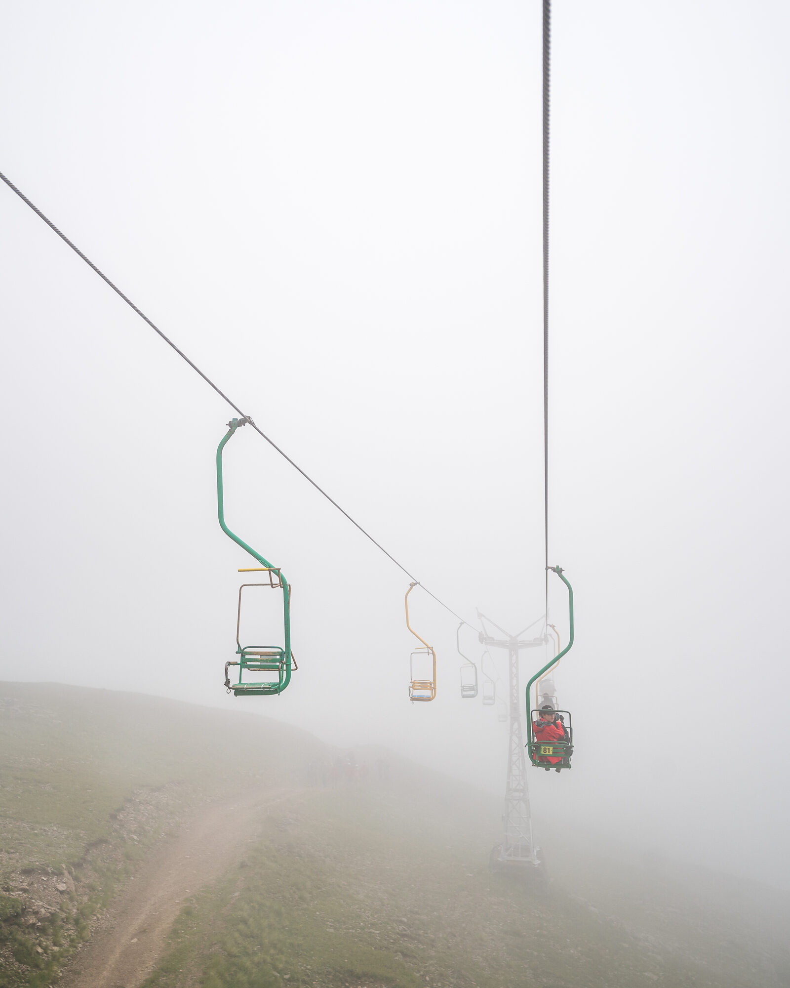 Old chairlift disappearing into thick fog on the Cheget slopes